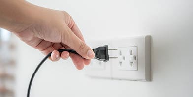Human hand put in or out electric plug in the socket to connect the devices. Household technology in use of human hand. Using of electric plug concept of safety, or environmental conservation.